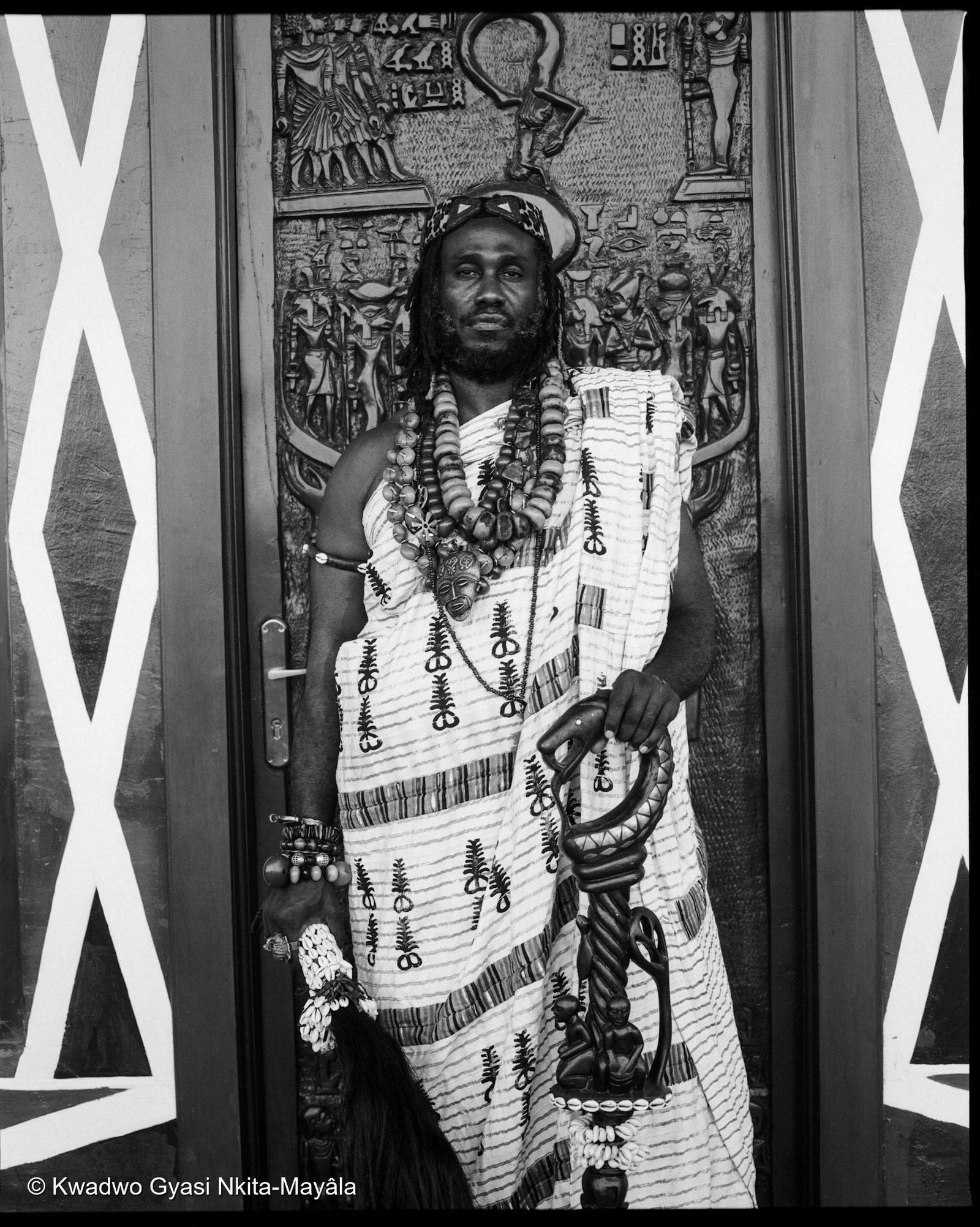 Ɔbenfo Ọbádélé Kambon standing in a symbolically decorated doorway